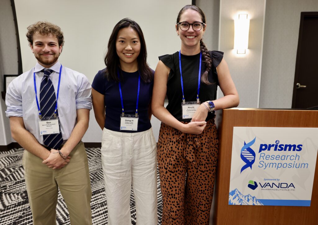 Three young scientists pose for a photo after a poster presentation.